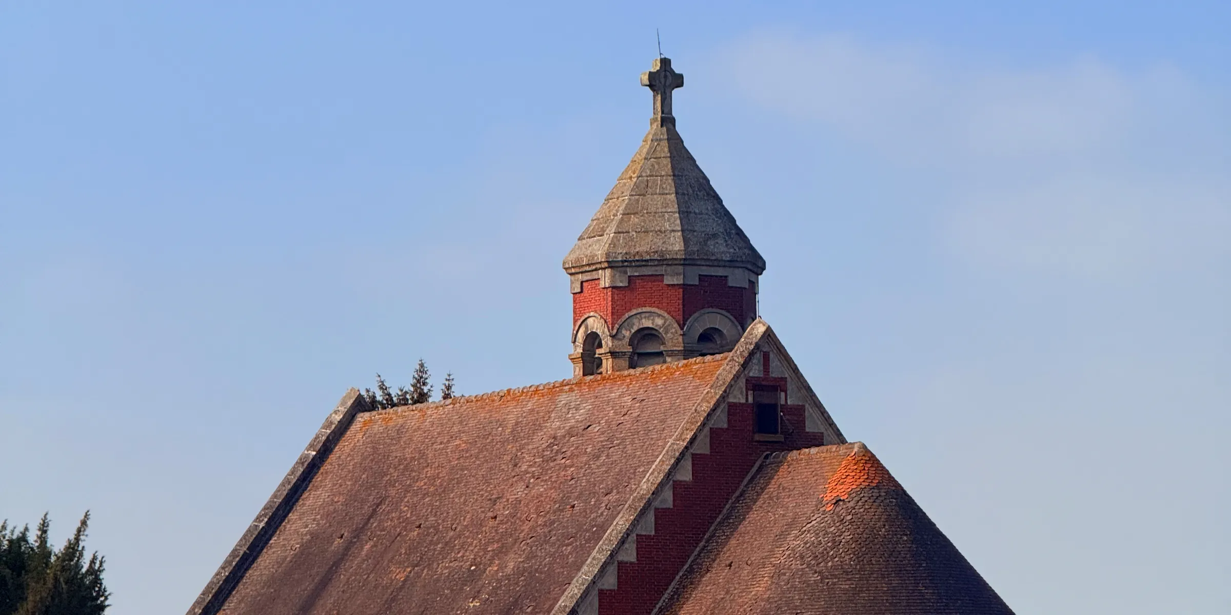 El tejado, el campanario pequeño y el ábside de la iglesia bajo un cielo azul